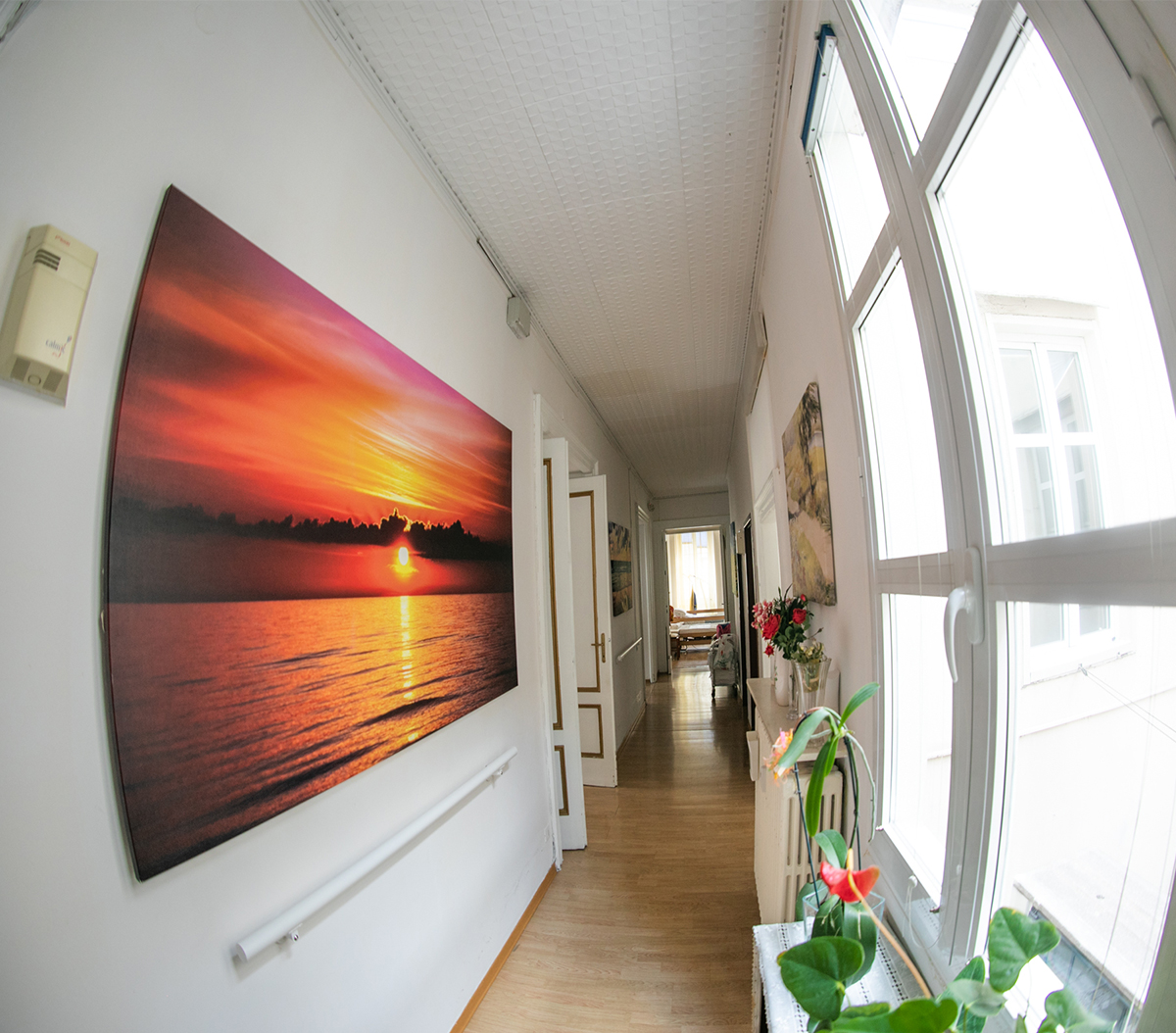 Corridoio luminoso con grandi finestre ad arco, opere d'arte a parete